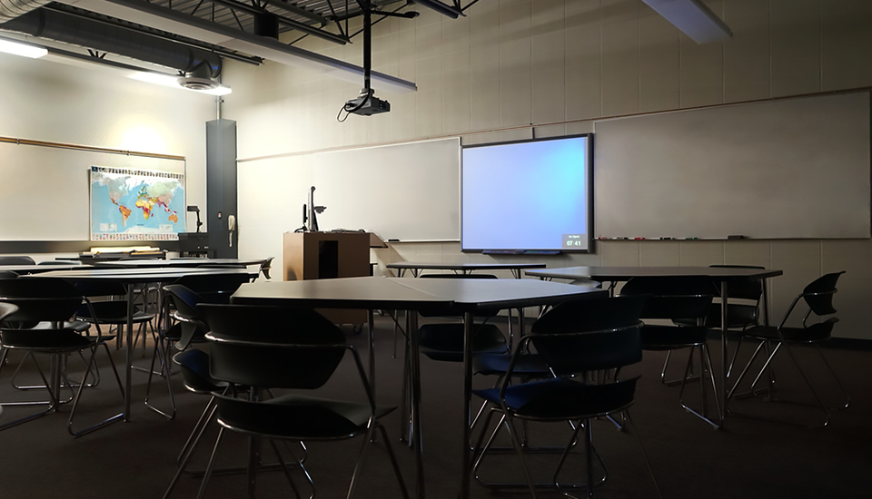 Large room with work tables, whiteboards and other technology for teaching.